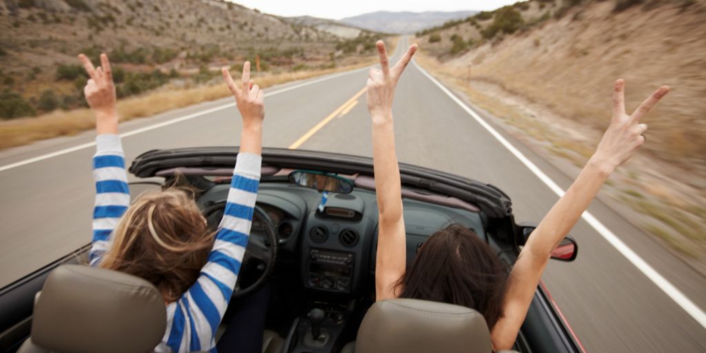 Hands up, while driving a convertible.